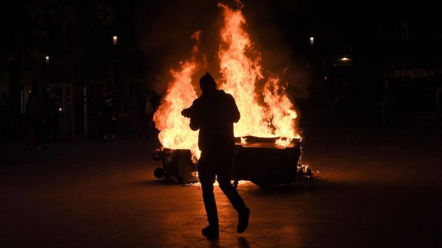  protestor walks next to burning bins during a demonstration a few days after the government pushed a pensions reform through parliament without a vote, using the article 49,3 of the constitution in Marseille, southern France. Credit: AFP Photo