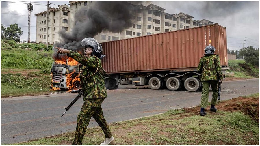 A Kenyan police officer calls for reinforcement in front of a lorry set on fire by protesters during riots in the informal settlement of Kibera in Nairobi on May 2, 2023. - Kenyan riot police were out on the streets on May 2, 2023 as the opposition defied a police ban and staged new demonstrations over the cost of living crisis and last year's election results. Credit: AFP Photo