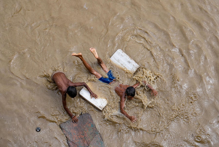 Children at play on a flooded road near the Red Fort as the swollen Yamuna river floods low-lying areas, in New Delhi. Credit: PTI Photo