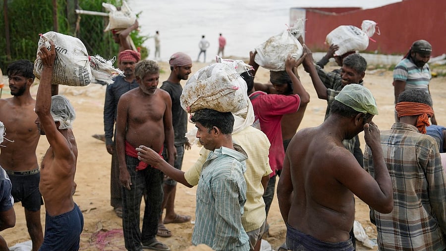 New Delhi: Workers load sandbags to be used for construction of an embankment near the drain regulator at ITO