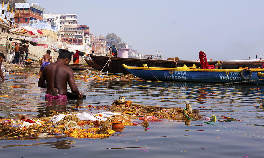 A man throwing his household garbage into River Ganga.