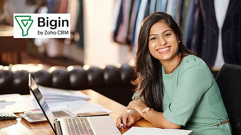 A lady working on a laptop with logo of Bigin by Zoho CRM in the corner