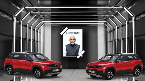 Display of two red SUVs with a poster of Prime Minister Narendra Modi in the background carrying the text “GST Discount,” symbolising GST-related price cuts in the automobile sector.