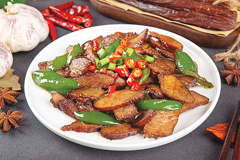 A imagem mostra pratos clássicos da culinária Xiang. No centro está a “cabeça de peixe ao vapor com malagueta picada”, rodeada por acompanhamentos como carne de porco salteada com malaguetas e legumes em conserva.