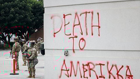 Membros da Guarda Nacional protegem edifício federal pichado com inscrição antifascista.