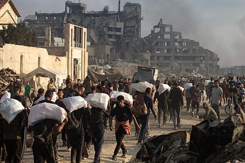 Palestinianos carregam ajuda humanitária em Gaza.