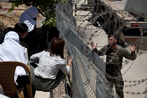 Mulheres drusas falam com um soldado israelita através da vedação na fronteira entre a Síria e Israel nos Montes Golã.