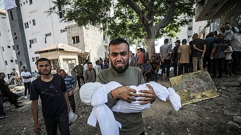 Um pai palestiniano carrega o corpo do filho, morto num bombardeamento israelita.