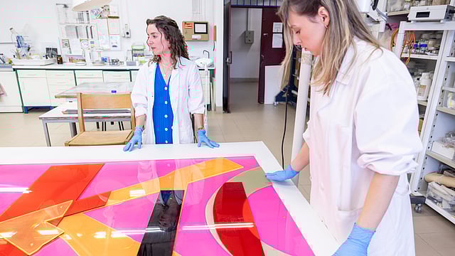 Suporte de folha de alumínio colada sobre cartão e madeira aparece atrás de Susana França de Sá (de azul), noutra mesa. 