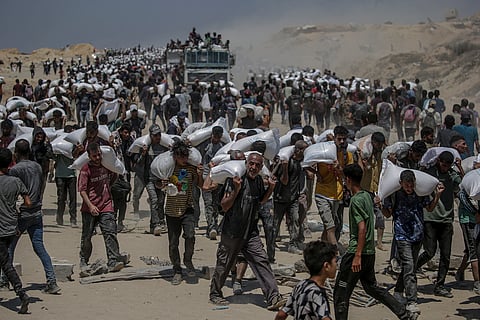 Palestinianos a carregar sacos de farinha em Zikim, na Faixa de Gaza, depois que Israel fez uma "pausa tática" nos ataques e permitiu a entrada de equipas para ajuda médica e distribuição de alimentos no domingo, 27 de julho. 