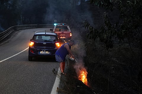 À beira da estrada, pouco depois de Vilarinho, na Lousã, uma mulher tenta apagar um pequeno foco de incêndio. Não teve de levar a tarefa até ao fim, porque apareceram os bombeiros, que completaram o que ela tinha começado.