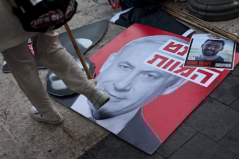 Cartaz com fotografia de Netanyahu no chão durante um protesto das famílias dos reféns contra o primeiro-ministro israelita.