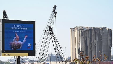 Um cartaz com a foto de Leão XIV onde se lê que “abençoados são os fazedores da paz” junto ao porto de Beirute, destruído por uma explosão em 2020. O papa rezará neste local.