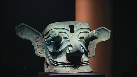 Máscara de bronze de olhos salientes descoberta em Sanxingdui, peça emblemática da cultura do bronze do antigo Reino de Shu, cujo estilo expressivo representa a figura divinizada de membros ou antepassados da família real.