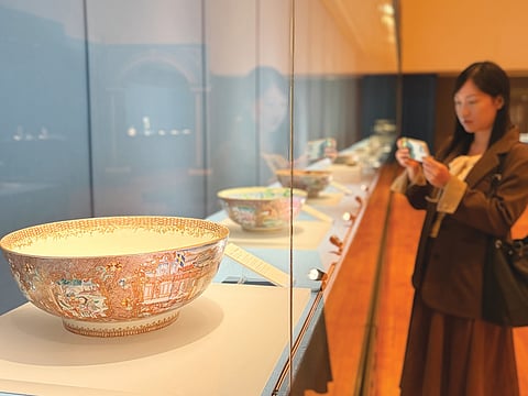 Visitante apreciando peças de porcelana em exposição.