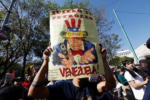 Um cartaz que retrata Trump a apontar a arma à Venezuela com a frase “Quero o teu petróleo” num protesto  no México contra os EUA. 