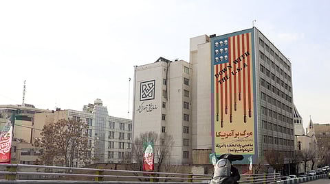 Iranianos passam de carro junto a um mural anti-EUA numa rua de Teerão. 