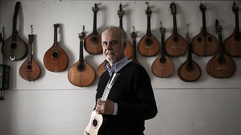 Pedro Caldeira Cabral junto a uma parte ínfima da sua coleção de cítaras, enquanto na mão segura um antepassado do cavaquinho.