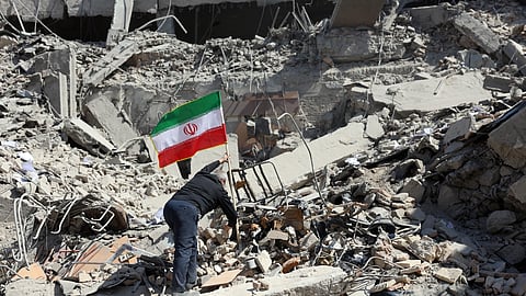 Um iraniano assinala com uma bandeira o que antes do bombardeamento era uma esquadra da polícia no centro de Teerão.