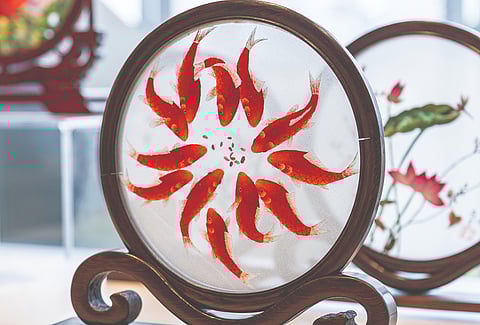 O motivo do peixe koi, um tema clássico do bordado Shu, simboliza abundância, prosperidade e fortuna.