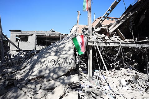 Uma bandeira iraniana  e a mensagem “No king” (referência às manifestações  anti-Trump) nos destroços de um edifício da Universidade Sharif, em Teerão, destruído por um bombardeamento.