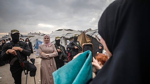 Uma mulher tira fotos com combatentes palestinianos em Gaza.