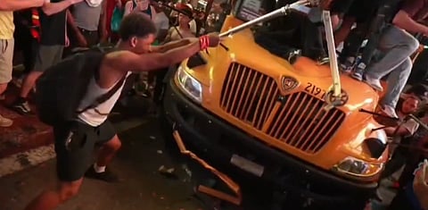 Homem a depredar um autocarro escolar durante a confusão após a vitória dos New York Knicks na final da NBA.