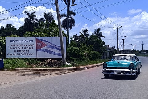 Um carro passa ao lado de um cartaz onde se lê que "a revolução é defender valores em que se acredita ao preço de qualquer sacrifício":