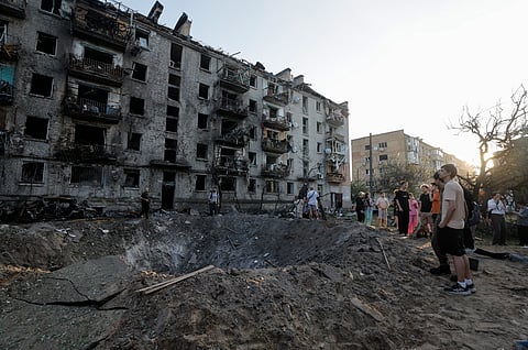 Moradores observam uma cratera no local de um ataque com míssil russo a uma zona residencial em Kiev.