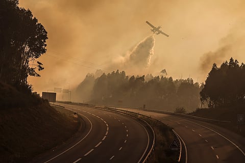 Um avião despeja água junto ao autoestrada A25, que esteve encerrada devdo ao incêndio de Vouzela