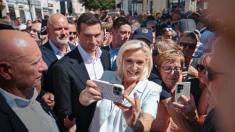 Le Pen, com Bardella ao lado, tira selfies com apoiantes no mercado de La Flèche.