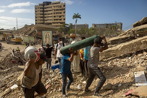 Voluntários e um padre continuam à procura de vítimas no meio dos destroços do duplo sismo de 24 de junho. 