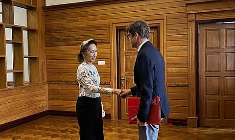 Aung San Suu Kyi com o líder local do Comité Internacional da Cruz Vermelha, Arnaud de Baecque.