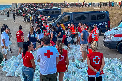 Funcionários da Cruz Vermelha distribuem alimentos para migrantes na praia El Trampolin, em Ceuta, Espanha