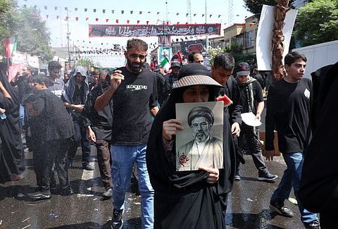 Mulher segura imagem de Mojtaba Khamenei.