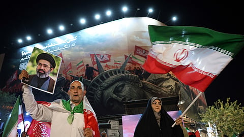 Um iraniano com uma foto do líder supremo num protesto em Teerão contra as sanções dos EUA.