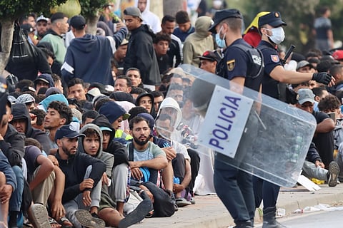 Polícias junto a migrantes em Ceuta no exterior de um dos centros de acolhimento temporários.