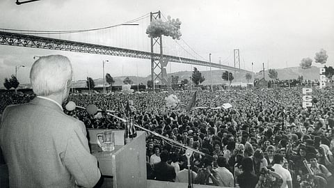 O histórico líder comunista Álvaro Cunhal discursa para  a multidão na 'Festa do Avante!', com a Ponte 25 de Abril  em plano de fundo, em 1976.