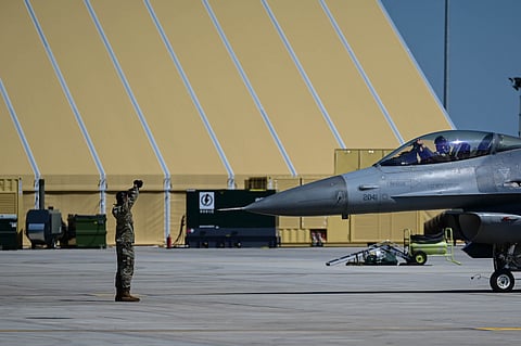 Um aviador norte-americano orienta a entrada de um F-16 durante um exercício militar em Câmpia Turzii, Roménia, maio de 2024.