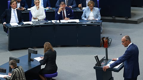 O chanceler Merz no púlpito, com a bancada da AfD ao fundo, incluindo a co-líder Alice Weidel (de branco).