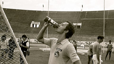 Franz Beckenbauer aproveita uma pausa no treino para se hidratar. O alemão, que ficou conhecido a jogar com líbero e ganhou a alcunha de Kaiser, era a grande estrela do Cosmos. Foi campeão do Mundo como jogador (1974) e como selecionador da Alemanha (1990). Morreu a 7 de janeiro de 2024, com 78 anos.