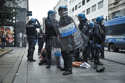 Manifestantes no chão, rodeados pela polícia de choque, em Milão.