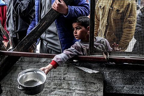 Criança em Rafah aguarda pela sua vez para receber uma refeição.