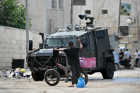 Um rapaz palestiniano levanta os braços perante um veículo militar israelita durante o raide em Jenin.