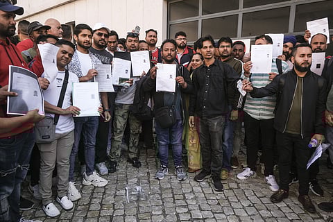 Trabalhadores mostram comprovativos de pedido de residência.