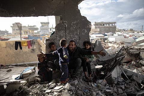 Um palestiniano e os filhos vivem no meio da destruição em Rafah.