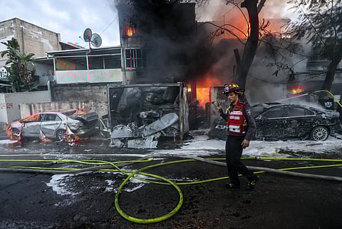 Bombeiros apagam o fogo após a queda de um rocket do Hezbollah.