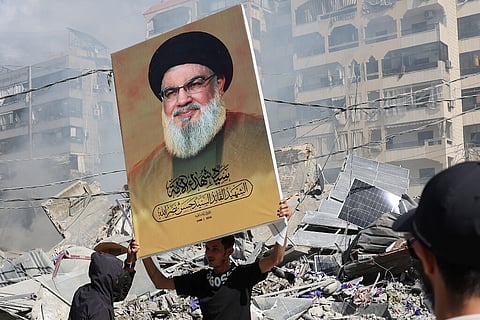 Um apoiante do Hezbollah mostra uma imagem de Nasrallah diante de um edifício destruído em Beirute.