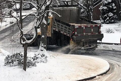 रोड पर जमा बर्फ को पिघलाने के लिए छिड़का जा रहा नमक; फोटो: सुजय कौशल 