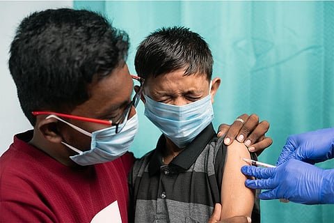 बच्चे को अस्पताल में कोविड-19 का टीका लगवाते माता-पिता; फोटो: आईस्टॉक